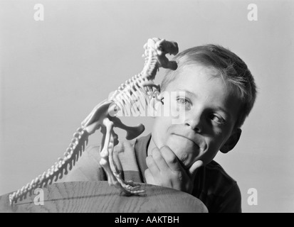 1960 garçon blond MAIN SUR MENTON à squelette de dinosaure Tyrannosaurus rex de modèle Banque D'Images