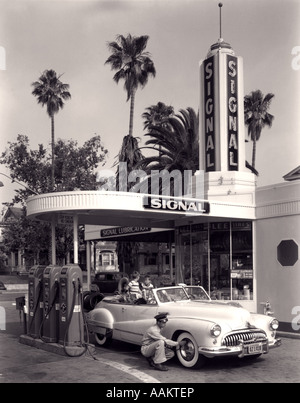 1950 FAMILLE EN VOITURE DÉCAPOTABLE PRÉPOSÉ DE STATION VÉRIFIER LE GONFLAGE DES PNEUS Banque D'Images