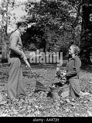 Années 1930 Années 1940 YOUNG TEEN COUPLE Garçon Fille RAKING Autumn Leaves Banque D'Images