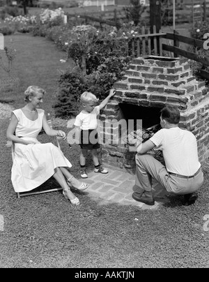 Années 1940 Années 1950 DANS LA COUR DE LA FAMILLE DES hamburgers de cuisson sur barbecue en brique Banque D'Images