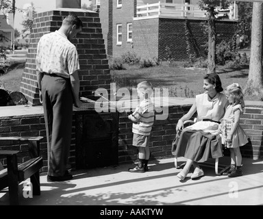 1950 SUR LA FAMILLE MURÉ PATIO DANS L'petit garçon HOT DOG CUISSON SUR BROCHETTE Banque D'Images