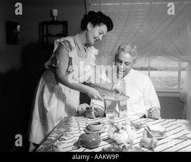 1950 femme portant un tablier SERVANT MARI ACCUEIL repas cuisiné à la fois SMILING PISCINE Banque D'Images