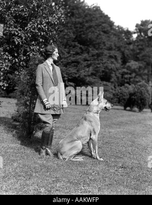 Années 1920 Années 1930 PROFILE PORTRAIT femme élégante portant des bottes d'ÉQUITATION TWEED CRAVATE COSTUME PERMANENT JODHPURS AVEC GREAT DANE DOG OUTDOOR Banque D'Images