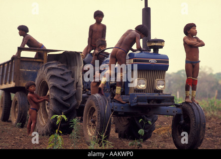 Xingu, forêt amazonienne, au Brésil. Yaulapiti les populations autochtones. Les enfants indigènes acculturés jouant sur le tracteur. Banque D'Images