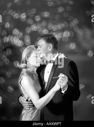 1960 COUPLE femme en robe de soirée et MAN IN TUXEDO DANSE LENTE Banque D'Images