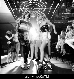 1970 COUPLE DISCO DANSE SUR PATINS À PORTER LES VÊTEMENTS À LA MODE SOUS UNE BOULE MIROIR Banque D'Images