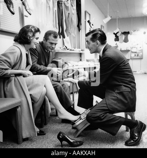 Années 1950 Années 1960 COUPLE MAN L'HOMME À LA CHAUSSURE CHAUSSURES IMPATIENT VENDEUR FAIT SON TRAVAIL Banque D'Images