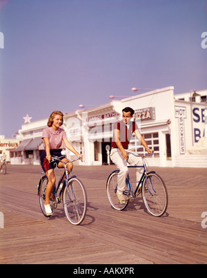 Années 1950, TEEN COUPLE RIDING BIKES SUR LA PROMENADE côte du New Jersey Banque D'Images