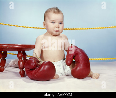 Années 1950 Années 1960 et couche-culotte bébé portant des gants de boxe en cuir ANTIQUE GRAND MALHEUREUX ASSIS AU COIN DE RING Banque D'Images