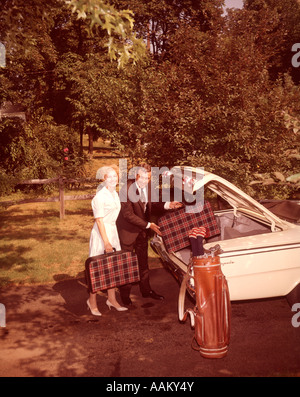 1960 COUPLE D'ÂGE MOYEN DE METTRE VOS BAGAGES DANS COFFRE DE VOITURE LOOKING AT CAMERA Banque D'Images