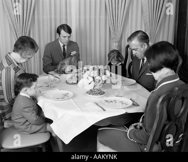 1960 TROIS GÉNÉRATION FAMILLE DISANT GRACE PRIÈRE À la dinde de Thanksgiving DINNER Banque D'Images