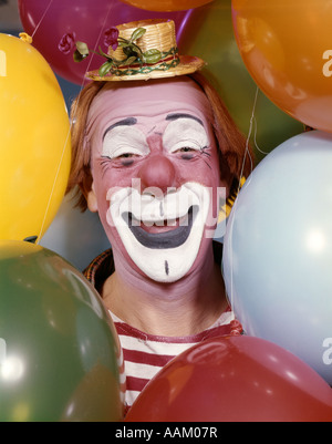 1960 Close-up PORTRAIT DE CLOWN ENTOURÉ PAR DES BALLONS Le visage souriant FOIRES CONCEPTION Drôle Banque D'Images