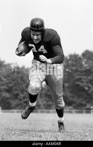 1940 FOOTBALL PLAYER HOLDING BALL EXÉCUTANT VERS LA CAMÉRA Banque D'Images