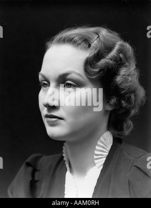 1930 PORTRAIT DE FEMME BRUNE À LA RECHERCHE SUR LE CÔTÉ AVEC UNE EXPRESSION VIDE PORTANT UN COLLIER FROISSÉ BLANC Banque D'Images