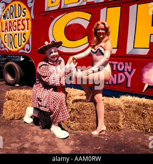 1970 WORLD'S LARGEST CIRCUS CLOWN HOMME AGENOUILLÉ FEMME DEBOUT ACROBAT Banque D'Images