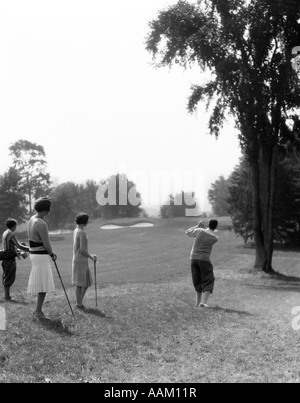 Années 1920 Années 1930 HOMME GOLFEUR AU BAS DE CONDUITE ET DEUX FEMMES FAIRWAY CADDY REGARDER Banque D'Images