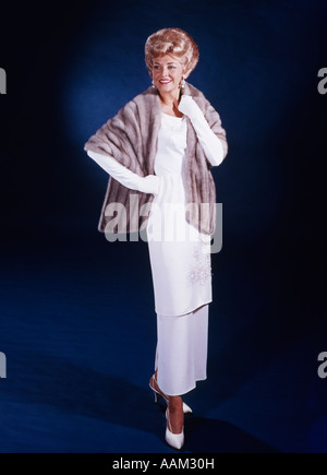 1960 BLONDE FEMME D'ÂGE MOYEN LONG ROBE BLANCHE portant des gants étole de fourrure vêtements pleine longueur élégante Banque D'Images