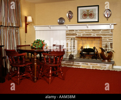 Années 1960 Années 1970, foyer au bois d'INTÉRIEUR EN PIERRE MOBILIER COLONIAL PAYS CHAISES TABLE TAPIS ROUGE DU MANTEAU D'APPLIQUES Banque D'Images