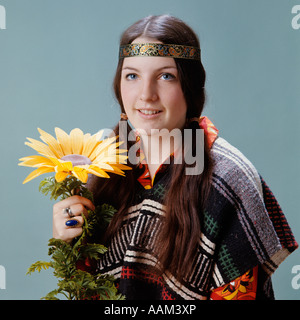 Années 1960 Années 1970 SMILING TEENAGE GIRL HIPPIE FLOWER CHILD WEARING HEADBAND AVEC DES NATTES ET SARAPE HOLDING STÉRÉOTYPE TOURNESOL Banque D'Images