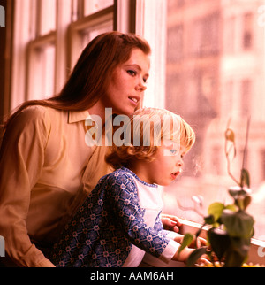 1970 1970 Mère Enfant à la fenêtre À REGARDER LES TOUT-PETITS tout-petits de mères de familles LA FAMILLE WINDOWS RETRO Banque D'Images