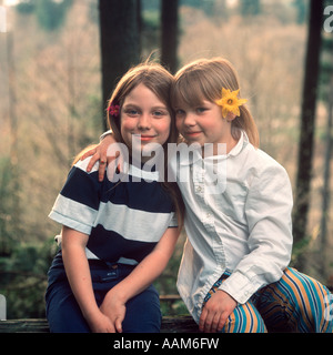 Deux jeunes filles avec des fleurs dans leurs cheveux assis dehors 1970 Rétro 1970 Banque D'Images