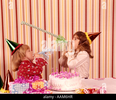 1970 1970 DEUX FILLES PARTY HATS BRUITS favorise le gâteau d'ANNIVERSAIRE CÉLÉBRER FÊTE GÂTEAUX PARTIES HEUREUX Banque D'Images