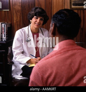 Des années 80, femme médecin INTERROGEANT AFRICAN AMERICAN MALE PATIENT Banque D'Images