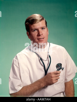 1960 PORTRAIT OF YOUNG DOCTOR HOLDING STETHOSCOPE LOOKING AT CAMERA Banque D'Images