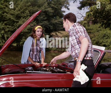 1960 COUPLE EN VOITURE AVEC LE CAPOT MOTEUR JUSQU'À LA À HOMME FEMME EXTÉRIEUR RÉPARATION HISTOIRE Banque D'Images