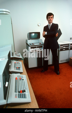 Années 80 RETRO PROGRAMMEUR HOMME DEBOUT DANS UNE SALLE AVEC DES CLAVIERS ÉCRANS MATÉRIEL TEXAS INSTRUMENTS Banque D'Images