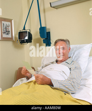 MAN PATIENT IN HOSPITAL BED OUVRIR MAIL RETRO 1970 1970 Banque D'Images