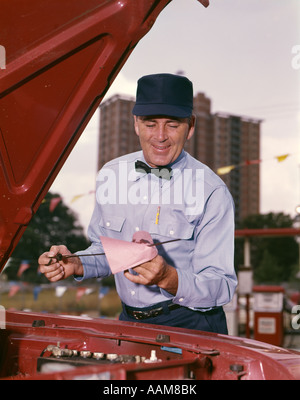 1960 1960 PRÉPOSÉ DE STATION SERVICE CONTRÔLE DE JAUGE À HUILE VOITURE ROUGE CONTRÔLE UNIFORME DE GAZ GARAGE RETRO VINTAGE Banque D'Images