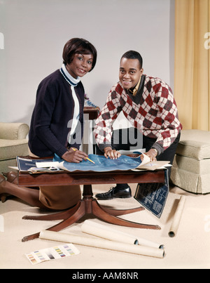 1960 AFRICAN AMERICAN COUPLE IN LIVING ROOM LOOKING AT BLUEPRINTS POUR NOUVELLE MAISON HOMME FEMME INTÉRIEURE PLAN Banque D'Images