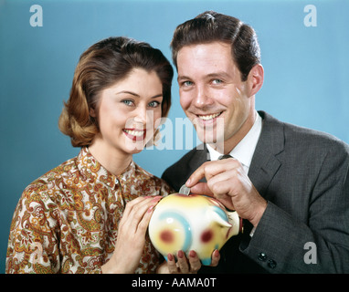 1950 HOMME FEMME SAUVER TRIMESTRE IN PIGGY BANK Banque D'Images