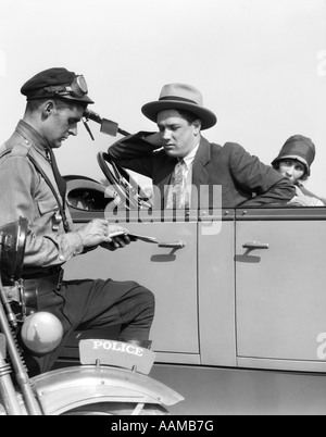 Moto 1920 POLICIER ÉCRIT UNE CONTRAVENTION À UN COUPLE SITTING IN CONVERTIBLE SEDAN Banque D'Images