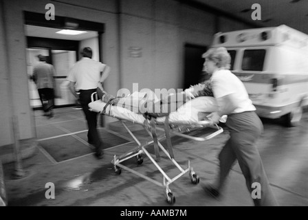 Des années 1980, l'équipe de l'EMT RUSHING PATIENT À l'hôpital sur une civière Banque D'Images