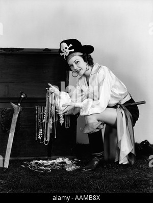 1940 WOMAN WEARING PIRATE COSTUME MONTRANT DES TRÉSORS DANS L'INTÉRIEUR DE FAISCEAUX Banque D'Images