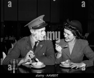 1940 SMILING COUPLE HOMME soldat en uniforme de l'Armée de terre et la femme blonde assise à la fontaine de SODA MANGER COMPTEUR PLAT DE LA CRÈME GLACÉE Banque D'Images