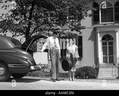 1940 HOMME FEMME LOADING COFFRE DE VOITURE AVEC VALISES ASSURANCE in front of house Banque D'Images