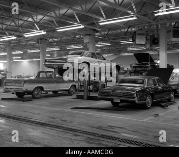 1960 GRAND GARAGE 2 VOITURES ET UN RAMASSEUR DE VOITURE EN MILIEU AVEC UN CRIC DE LEVAGE HYDRAULIQUE PAR Banque D'Images