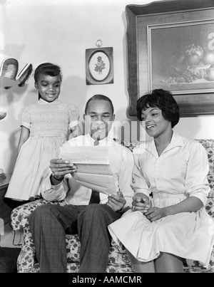 1960 AFRICAN AMERICAN FAMILY ON COUCH READING LETTRE OU D'ASSURANCE Mère Père fille Banque D'Images