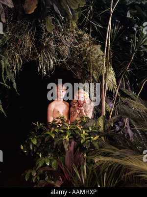 1970 HOMME FEMME COUPLE ADAM EVE SILLY FEUILLAGE JUNGLE PERMANENT HOLDING APPLE SIN JARDIN D'EDEN FUNNY CHARACTER Banque D'Images