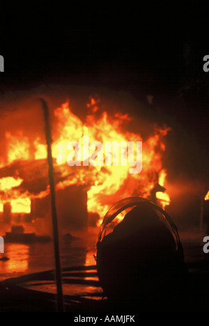 Fire fighter mettant de l'eau sur l'incendie d'une maison Banque D'Images