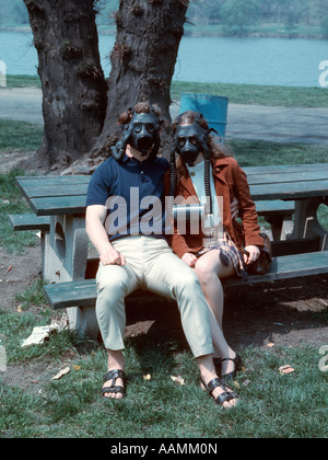 COUPLE SITTING ON PARK BENCH portant des masques à gaz Banque D'Images
