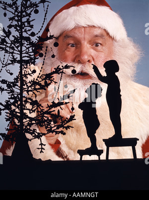 La silhouette anonyme petit garçon et fille à la recherche de l'ARBRE DE NOËL JUSQU'AU VISAGE DU PÈRE NOËL EN ARRIÈRE-PLAN LOOKING AT CAMERA Banque D'Images