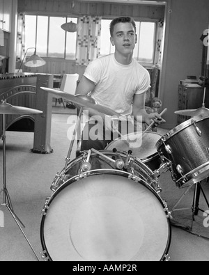 1960 TEEN BOY AVEC BUZZ CUT EN T-SHIRT ASSIS DEVANT DES PETITS BÂTONS SUR LE KIT DE BATTERIE HOLDING SNARE Banque D'Images