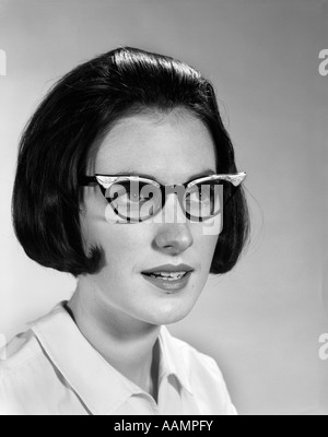 1960 PORTRAIT YOUNG BRUNETTE WOMAN WEARING EYEGLASSES FRAME MODE Banque D'Images