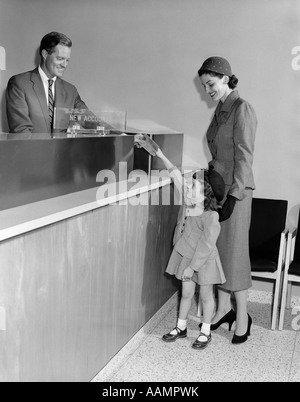 1950 MAN TELLER NOUVEAUX COMPTES EN BANQUE MÈRE FEMME AVEC PETITE FILLE FILLE MAINS PASSBOOK Banque D'Images