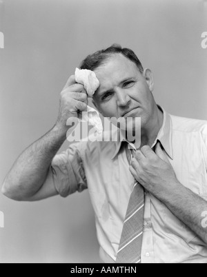 Années 1940 Années 1950 La transpiration dans l'homme retroussé les manches de chemise CRAVATE DESSERRANT HOLDING MOUCHOIR ESSUYANT FRONT LOOKING AT CAMERA Banque D'Images