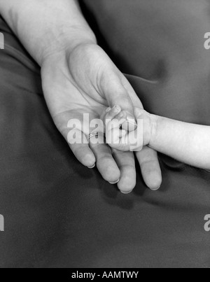 Années 1950, close-up of BABY HOLDING MOTHER'S THUMB Banque D'Images